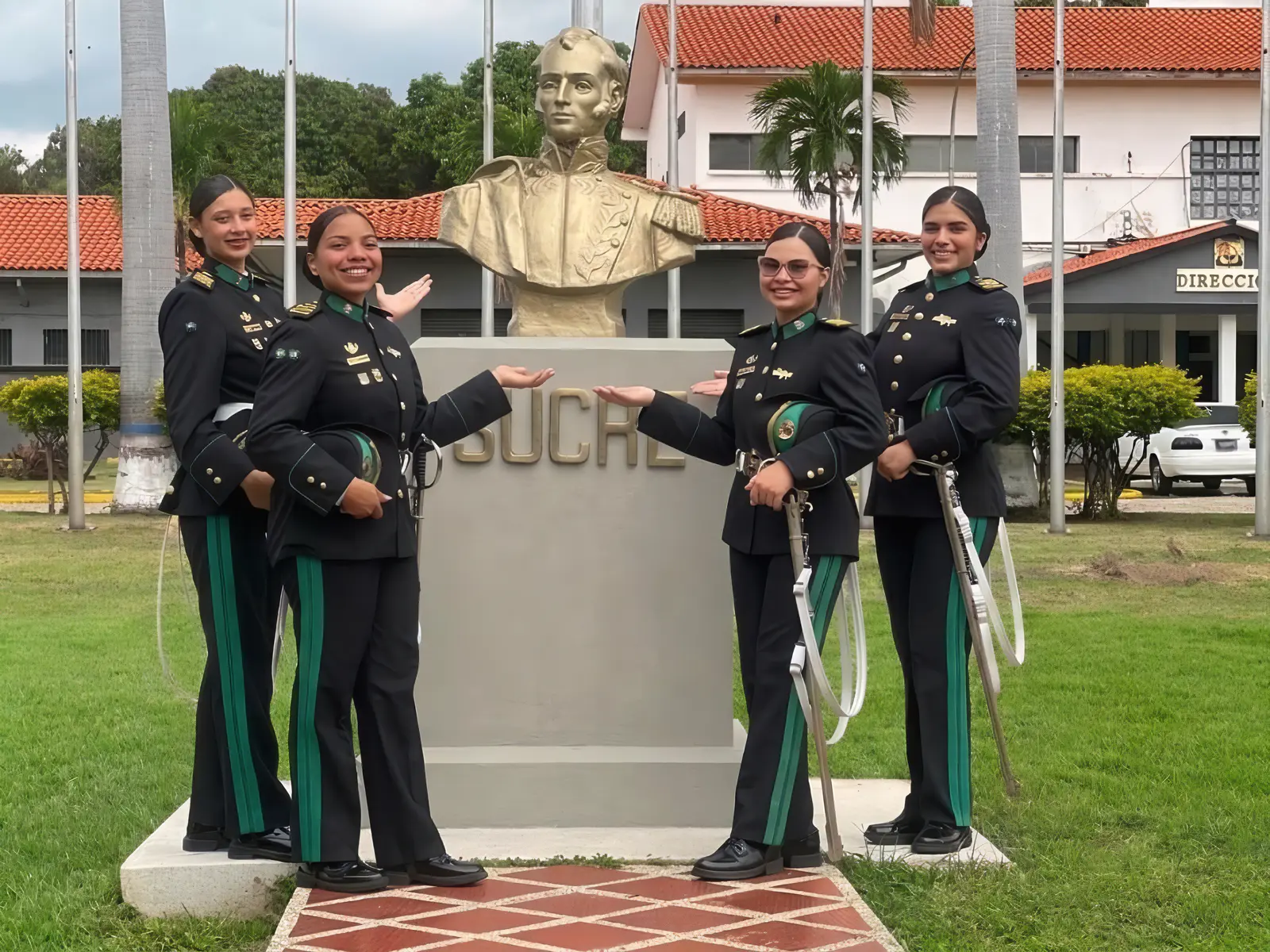 Cuatro cadetes con uniforme de gala junto al busto del Mariscal Sucre en la academia